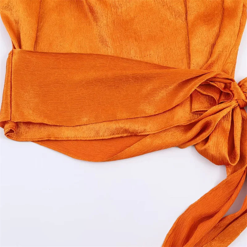 Women's top, Spring 2026 novelty: orange sleeveless design with satin texture and long tie; an elegant, stylish, and unique garment that sets the trend.
